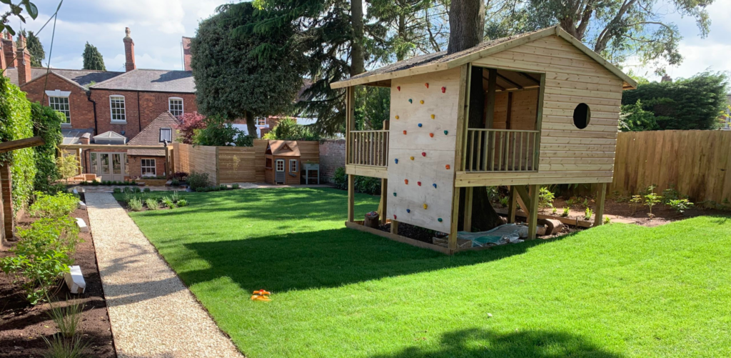 Bespoke timber treehouse construction with climbing wall and child play area integrated into landscaped garden design
