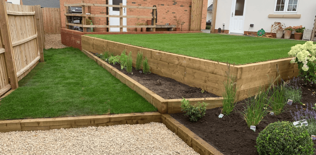 Garden terracing and soil grading project featuring raised sleeper beds, fresh turf installation, and gravel hardscaping