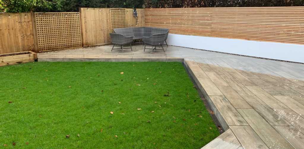 Modern garden redesign with multi-tiered porcelain patio slabs, contemporary slatted timber screening, and woven outdoor furniture