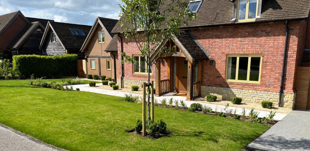 Rivermead in Bidford-on-Avon residential front and back garden re-design - Front garden lawn, resin driveway, planting beds, trees and bushes planted.