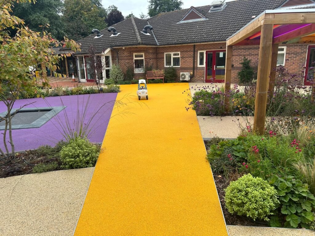 Acorn Hospice in Walsall Commercial Landscaping Project - Resin footpaths, wooden garden structure, outdoor pergola, climbing frames, new turf. New planting plan and flower beds. Stone pathway and patios. Custom made sunken trampoline for children.