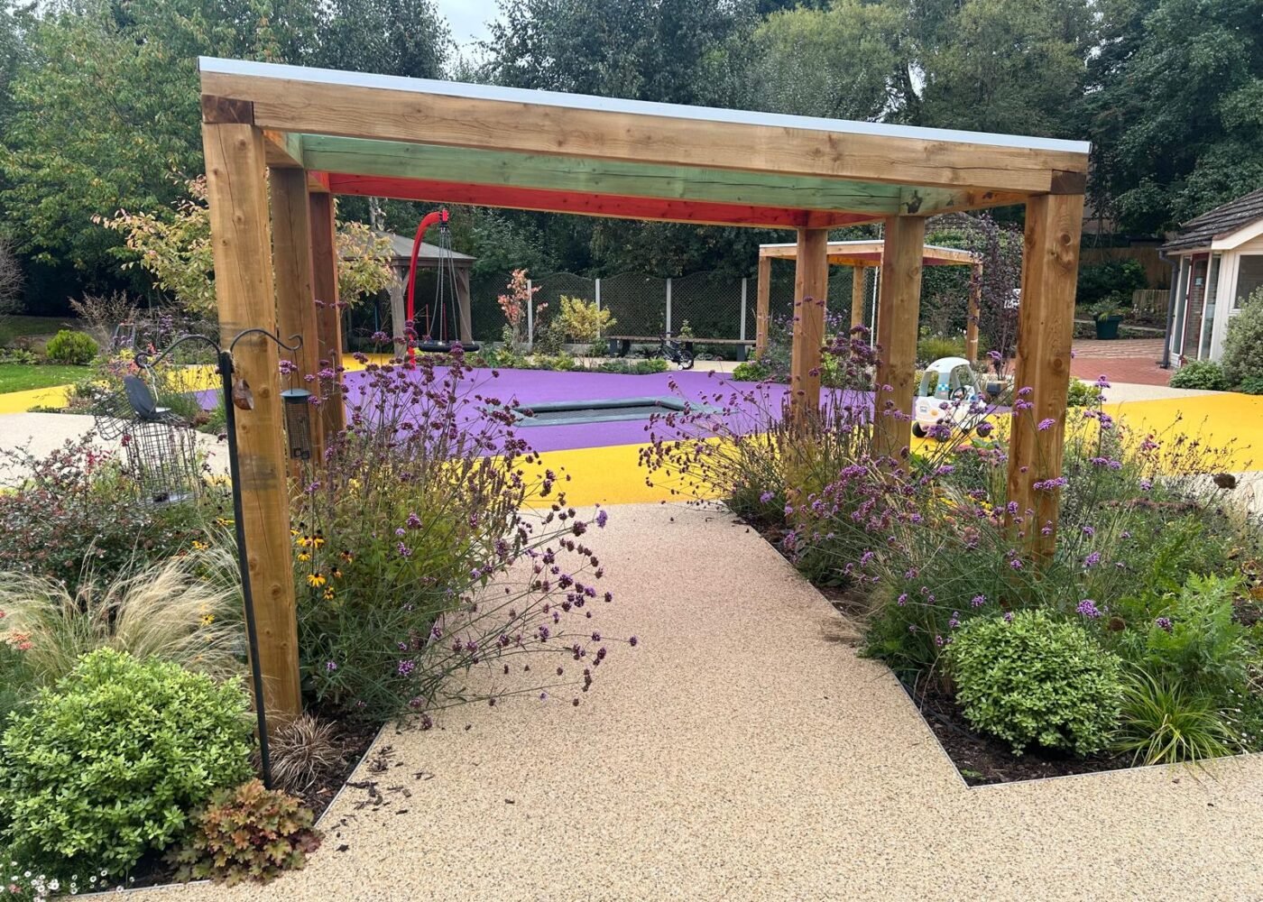 Acorn Hospice in Walsall Commercial Landscaping Project - Resin footpaths, wooden garden structure, outdoor pergola, climbing frames, new turf. New planting plan and flower beds. Stone paths way and patios. Custom made timber pergola
