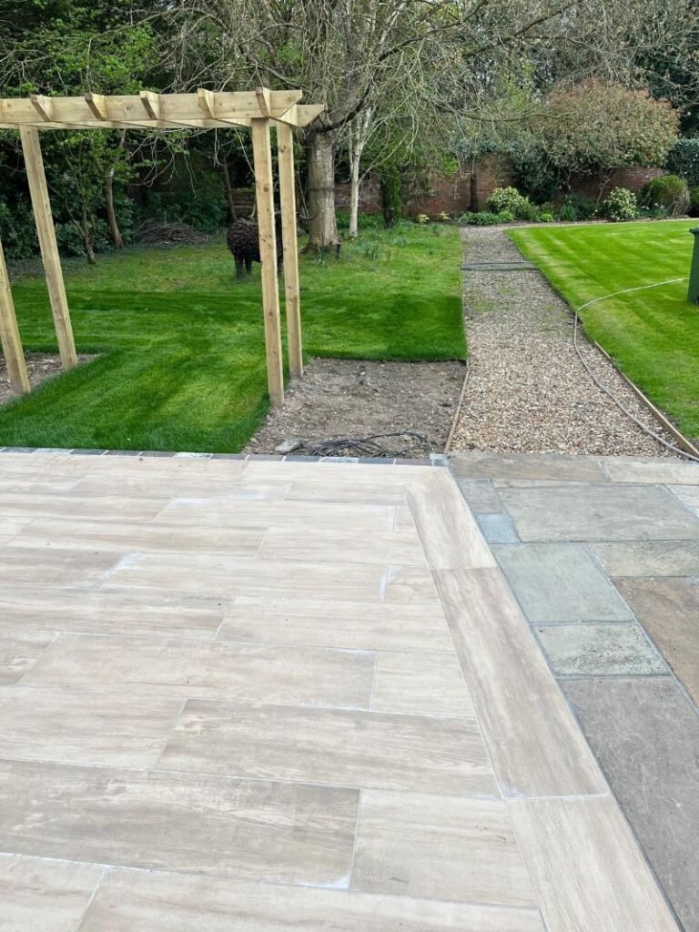 Modern garden design with wood-effect porcelain patio paving, natural stone pavers, and timber pergola structure