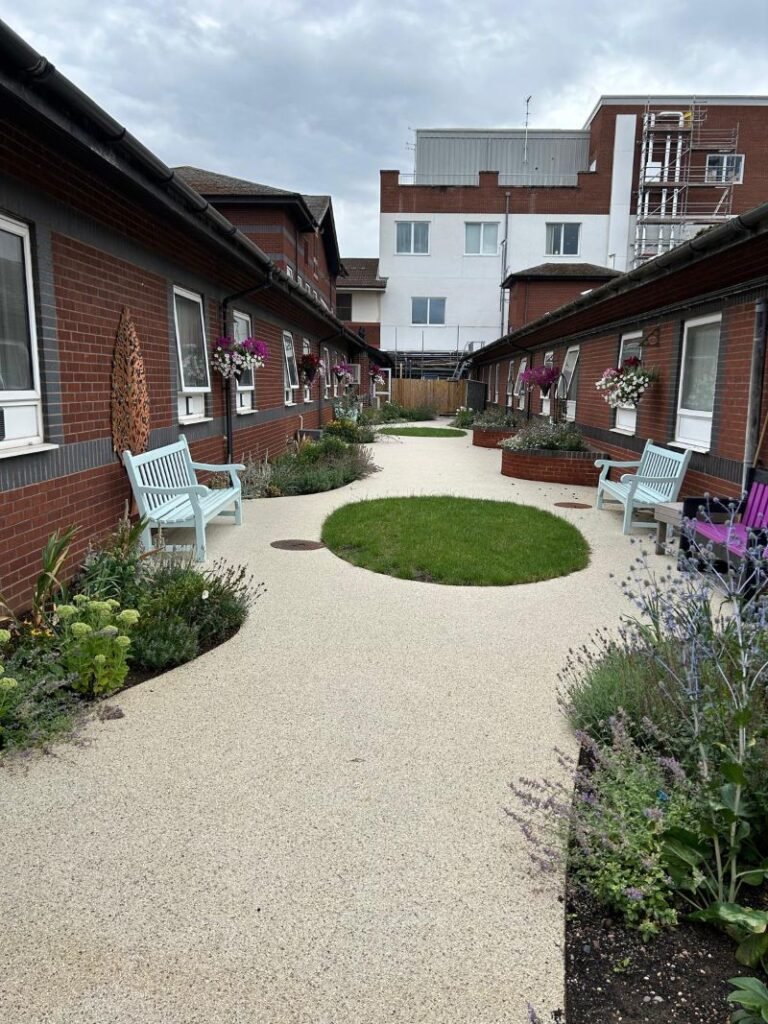 Modern landscaped courtyard featuring permeable resin bound gravel pathway with circular lawn inserts and lavender planting
